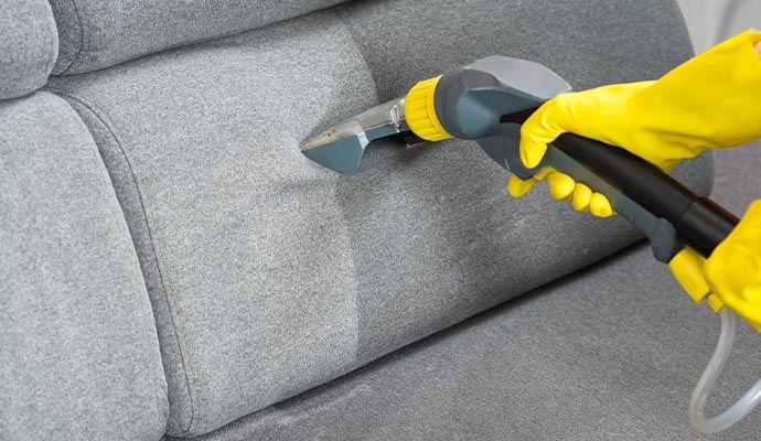 Person cleaning upholstery with equipment