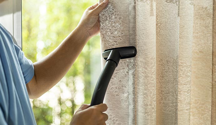 Person cleaning drapery with equipment