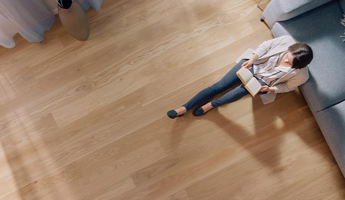 A person reading book sitting on the clean wooden floor