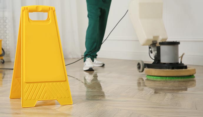 Expert worker cleaning wooden floor